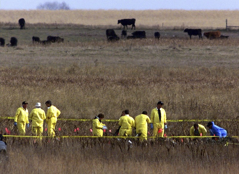 FILE - A crew of workers supervised by the National Transportation Safety Board place flags among the wreckage of a private jet transporting Payne Stewart in a farm field near Mina, S.D., Oct. 26, 1999. Some aviation experts are citing pilot hypoxia as a leading theory for why an unresponsive business plane flew over the nation’s capital on Sunday, June 4, 2023, and caused the military to scramble fighter jets. One of the most well-known crashes involving hypoxia was the 1999 crash of a Learjet that lost cabin pressure and flew halfway across the country on autopilot before running out of gas and crashing in a South Dakota pasture, killing professional golfer Stewart and five others. (AP Photo/Dave Weaver, File)