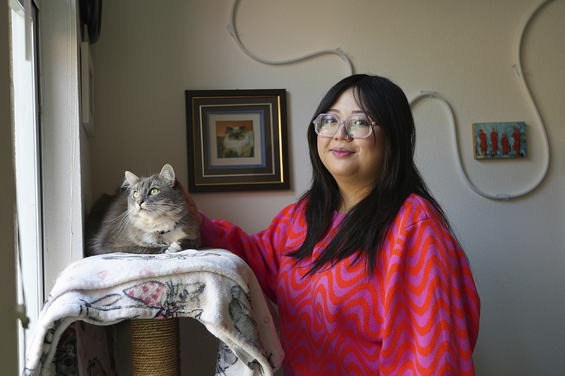 Celina Chanthanouvong stands with her cat in her apartment in Emeryville, Calif., on June 2, 2023. After a payment pause that has lasted more than three years, more than 40 million student loan borrowers will be on the hook for payments starting in late August. The pause in repayment has been a lifeline keeping 25-year-old Chanthanouvong afloat. (AP Photo/Terry Chea)