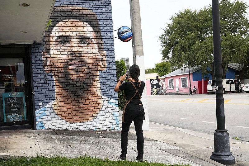 Jessica Ospina takes a photograph of a mural of Lionel Messi outside of the Fiorito restaurant Wednesday in Miami. (Associated Press)