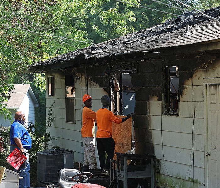 Employees with the city of Little Rock prepare to install plywood over a window at a house at 4800 Greenfield Drive where four people were found dead by firefighters responding to a fire early Friday.
(Arkansas Democrat-Gazette/Colin Murphey)