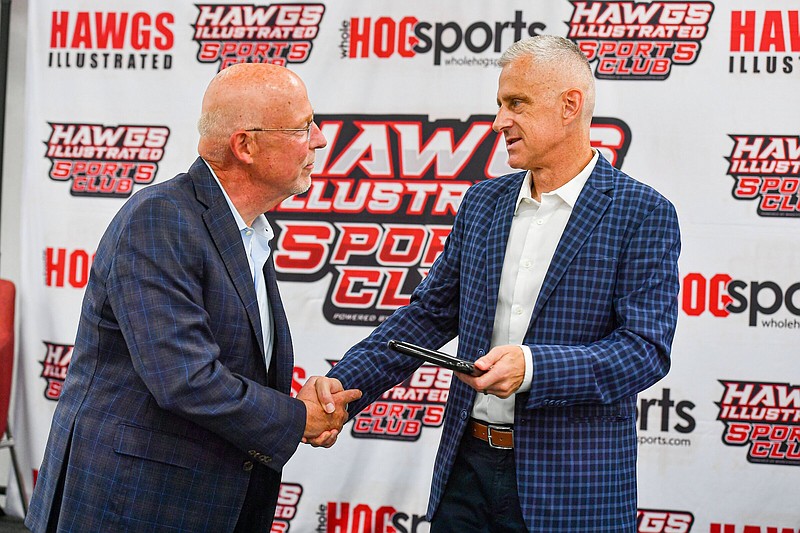 Chuck Barrett (left) and George Schroeder shake hands Wednesday during an induction ceremony into the Arkansas Sportscasters and Sports Writers Hall of Fame at a Hawgs Illustrated Sports Club luncheon inside the Home2 Suites by Hilton in Bentonville.
(NWA Democrat-Gazette/Hank Layton)