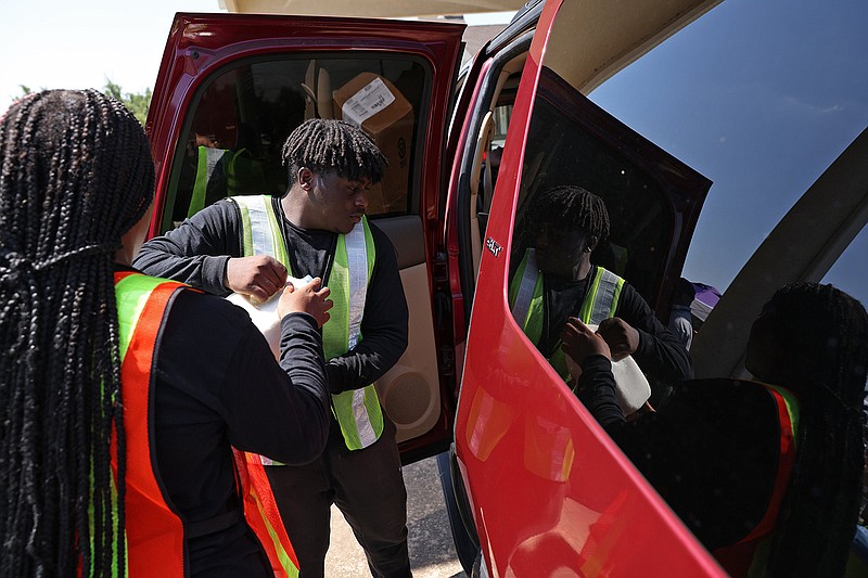 Antoine Ingram, center left, helps other volunteers load food into vehicles during the Arkansas Martin Luther King Jr. Commission Pre-Fourth of July Food Giveaway event at the St. Luke Baptist Church in North Little Rock on Monday, July 3, 2023. (Arkansas Democrat-Gazette/Colin Murphey)