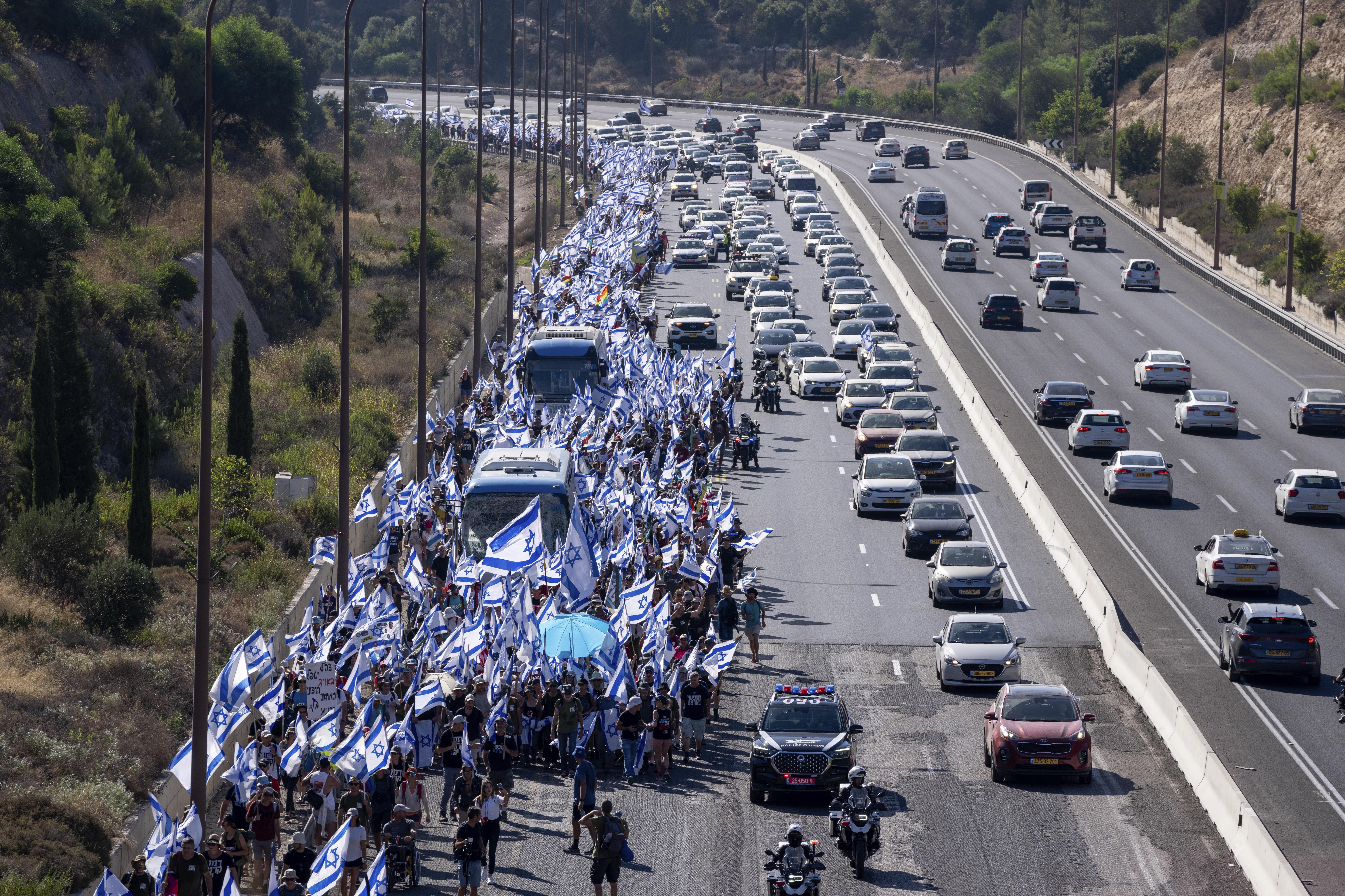 Israelis march along Highway 1 on their way to Jerusalem near Moshav Shoresh in Israel, as part of protests against plans by Prime Minister Benjamin Netanyahu's government to overhaul the judicial system, Friday, July 21, 2023. The protest march from Tel Aviv to Jerusalem is growing as Netanyahu vows to forge ahead on the controversial overhaul. Protest organizers planned to camp overnight at Shoresh, before making their way to Israel's parliament on Saturday. (AP Photo/Ohad Zwigenberg)