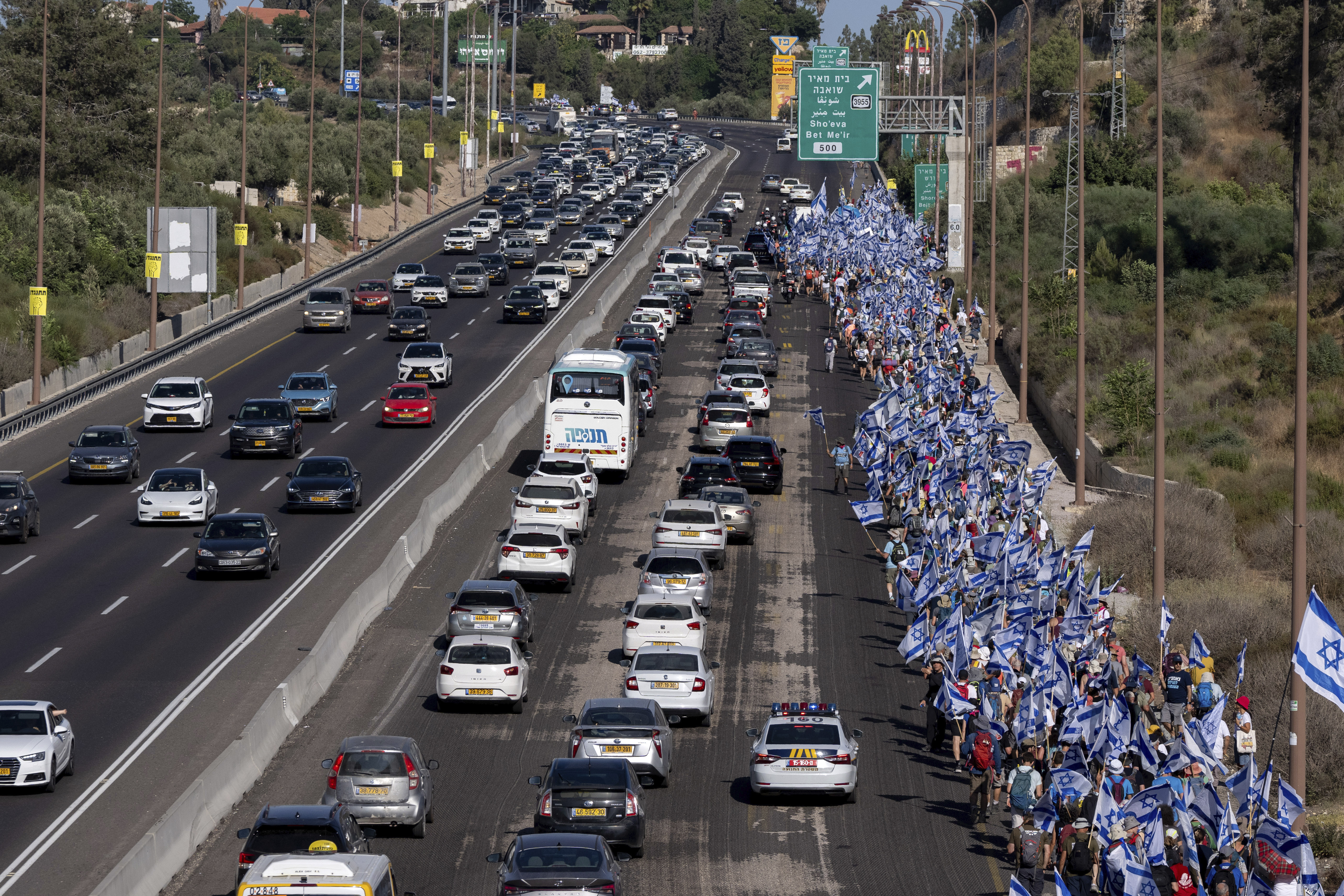 Israelis march along Highway 1 on their way to Jerusalem near Moshav Shoresh in Israel, as part of protests against plans by Prime Minister Benjamin Netanyahu's government to overhaul the judicial system, Friday, July 21, 2023. The protest march from Tel Aviv to Jerusalem is growing as Netanyahu vows to forge ahead on the controversial overhaul. Protest organizers planned to camp overnight at Shoresh, before making their way to Israel's parliament on Saturday. (AP Photo/Ohad Zwigenberg)
