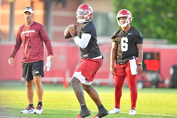 Arkansas quarterback KJ Jefferson (center) throws while offensive coordinator Dan Enos (left) and quarterback Jacolby Criswell watch during practice Friday, Aug. 4, 2023, in Fayetteville.