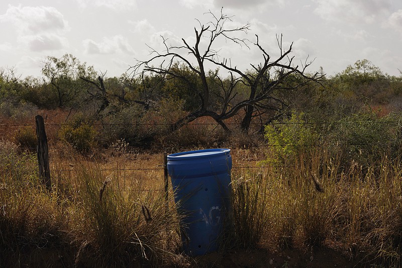 A water station for immigrants containing sealed jugs of fresh water sits along a fence line near a roadway in rural Jim Hogg County, Texas, Tuesday, July 25, 2023. The South Texas Human Rights Center maintains over 100 blue barrels consistently stocked with water across rural South Texas to serve as a life-saving measure for immigrants who have crossed into the United States to travel north in the sweltering heat. (AP Photo/Michael Gonzalez)