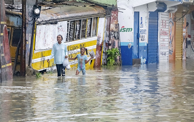 People walk through a street flooded by the rains of Tropical Storm Franklin in Santo Domingo, Dominican Republic, Tuesday, Aug. 22, 2023. (AP/Ricardo Hernandez)