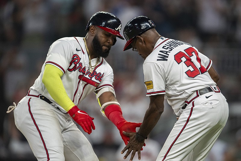 Atlanta Braves' Marcell Ozuna slap hands with third base coach Ron Washington, right, after hitting a home run against the New York Mets during the seventh inning of a baseball game Wednesday, Aug. 23, 2023, in Atlanta. (AP Photo/Hakim Wright Sr.)