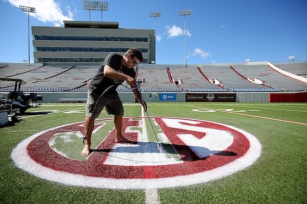Josh Oliver paints the SEC logo on the field at War Memorial Stadium on Wednesday, Oct. 10, 2018, in Little Rock.