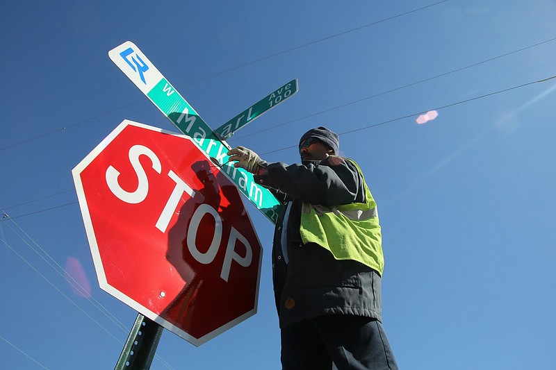 Wilson Johnson of Little Rock Public Works puts the finishing touches on new street signs at the intersection of Pearl Avenue and West Markham Street in Little Rock in this January 2016 file photo. (Arkansas Democrat-Gazette file photo)