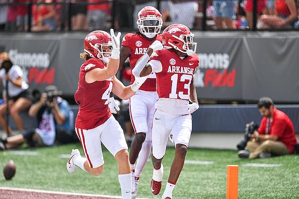 Arkansas wide receiver Jaedon Wilson (13) celebrates with teammates Isaac TeSlaa (4) and Andrew Armstrong (2) after scoring a touchdown reception, Saturday, Sept. 2, 2023, during the first quarter against Western Carolina at War Memorial Stadium in Little Rock.