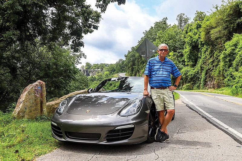 Staff photo by Olivia Ross / Eddie Rahm, who created a website showcasing 17 day trip loops in the Chattanooga area for his project Scenic City Backroads, stands next to his Porsche on a Lookout Mountain pull off on Friday, July 21, 2023.