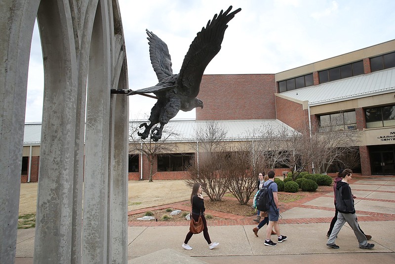 Students walk near the Learning Resource Center on the campus of John Brown University in Siloam Springs in this Feb. 27, 2018 file photo. The students had just left the Cathedral of the Ozarks. In the foreground is a statue of an eagle, representing the school's Golden Eagles mascot. (NWA Democrat-Gazette/David Gottschalk)