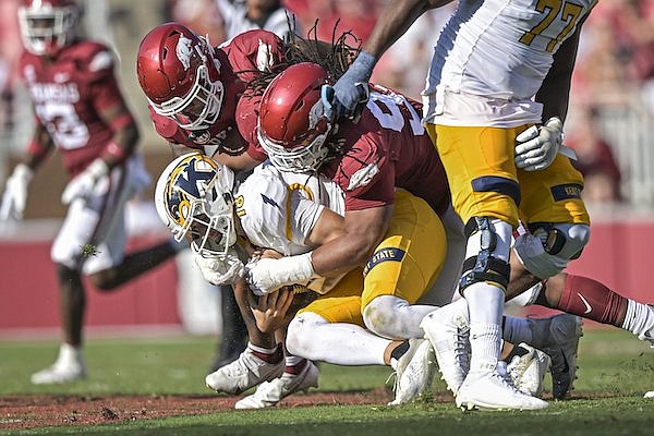 Arkansas defenders Keivie Rose (right) and Chris Paul sack Kent State quarterback Michael Alaimo during a game Saturday, Sept. 9, 2023, in Fayetteville.