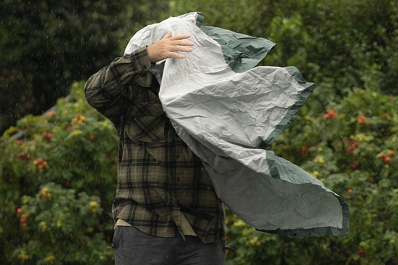 A tourist struggles with his rain poncho in strong wind as weather associated with Storm Lee hits the region, Saturday, Sept. 16, 2023, in Bar Harbor, Maine. (AP/Robert F. Bukaty)