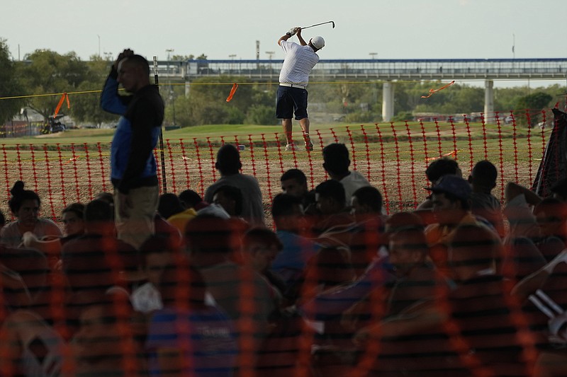 A golfer hits a shot Thursday at a golf course near a makeshift processing area along the Rio Grande at Eagle Pass, Texas, in front of an audience of migrants who crossed the border from Mexico.
(AP/Eric Gay)