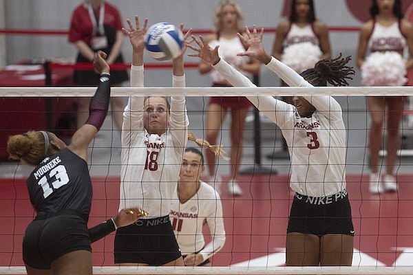Arkansas’ Hannah Hogue (18) and Sania Petties go up to block a hit by Texas A&M’s Bianna Muoneke on Sunday Sept. 24, 2023 at Barnhill Arena in Fayetteville.