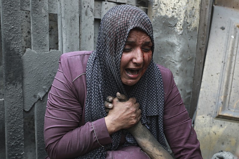 A wounded Palestinian woman cries as she holds the hand of her dead relative outside her home following Israeli airstrikes that targeted their neighbourhood in Gaza City, Monday, Oct. 23, 2023. (AP Photo/Abed Khaled)