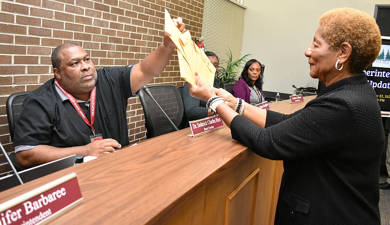 Pine Bluff School District board Chair Sederick Charles Rice draws an election lot from Pine Bluff Mayor Shirley Washington at the start of a board meeting Monday, Oct. 24, 2023. Rice's term will expire November 2028. (Pine Bluff Commercial/I.C. Murrell)