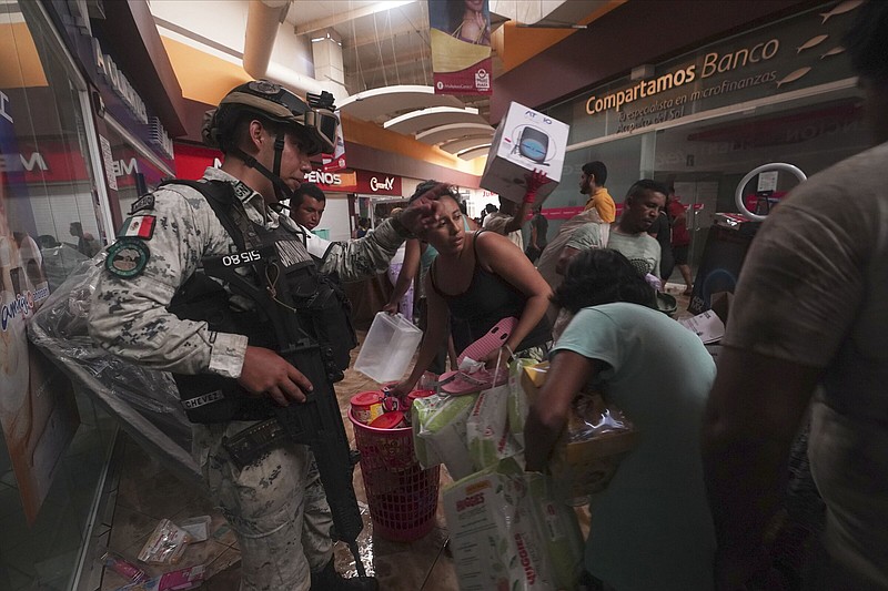 A Mexican National Guard soldier tries to stop people carrying away items like diapers and canned goods Wednesday, while others take electronics from a store at a shopping mall after Hurricane Otis ripped through Acapulco, Mexico.
(AP/Marco Ugarte)