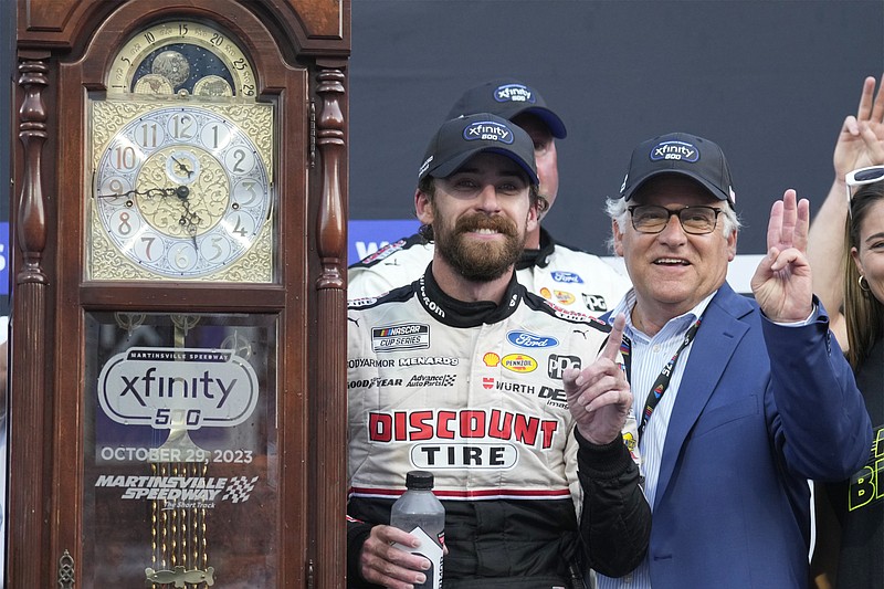 Ryan Blaney, left, poses with the trophy grandfather clock after winning a NASCAR Cup Series auto race at Martinsville Speedway in Martinsville, Va., Sunday, Oct. 29, 2023. (AP Photo/Chuck Burton)