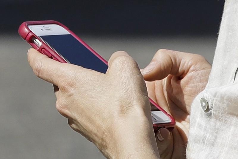 A woman browses her smartphone in this April 8, 2019 file photo. Americans lose billions of dollars annually to scammers who find their victims on cellphones and landlines, according to Truecaller Insights. (AP/Matt Rourke)