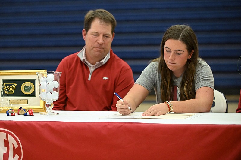 In this file photo Anna Kate Nichols (right) signs her national letter of intent to play golf for the University of Arkansas as her father Joey looks on during a signing ceremony at Pulaski Academy’s Alex Hugg Gymnasium in Little Rock. Nichols won back-to-back Overall state championships her junior and seasons with the Lady Bruins.
(Arkansas Democrat-Gazette/Staci Vandagriff)