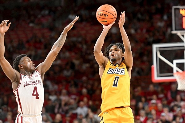 UNC Greensboro guard Keyshaun Langley (0) shoots over Arkansas guard Davonte Davis (4) during the first half of an NCAA college basketball game Friday, Nov. 17, 2023, in Fayetteville, Ark. (AP Photo/Michael Woods)