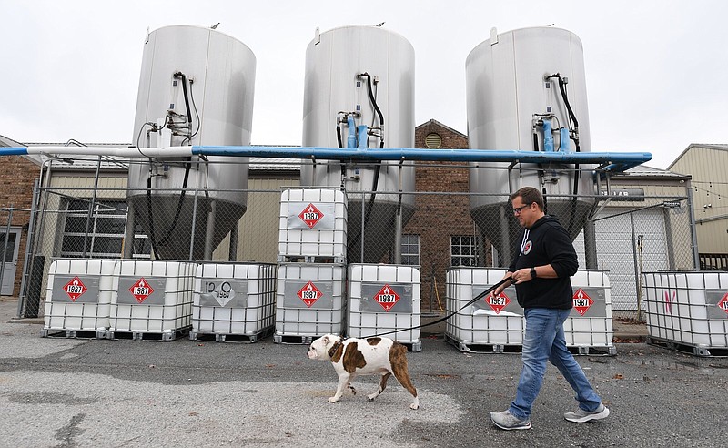 Jesse Core, founder of Core Brewing and Distilling Company, walks Larry, his dog and the company’s official “morale officer” at the company’s facility in Springdale on Tuesday.
(NWA Democrat-Gazette/Andy Shupe)
