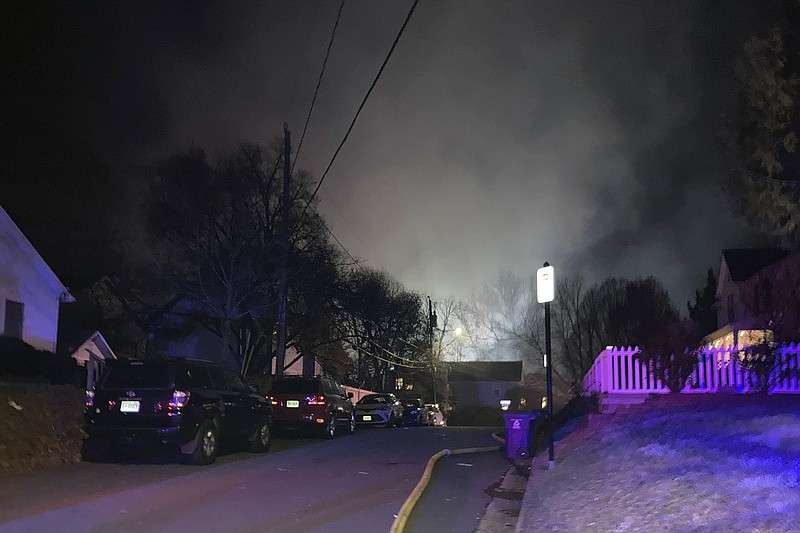 Smoke rises over a neighborhood where Virginia police say a house exploded as officers were trying to serve a search warrant on Monday, Dec. 4, 2023, in Arlington, Va. (AP Photo/Matthew Barakat)