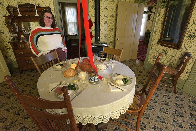 Ashley Sayers, education manager at the Rogers Historical Museum, shows Christmas dinner Saturday Dec. 2 2023  in the dining room of the Hawkins House..(NWA Democrat-Gazette/Flip Putthoff)