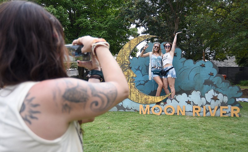 Staff photo by Matt Hamilton/ Charlotte resident Marissa Ahler takes a picture of Dani Womack and Kristin Hoffman, right, of Wilmington, N.C. during the first day of the Moon River music festival in Coolidge Park on Saturday, September 9, 2023.