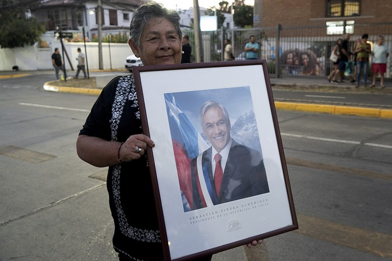 A supporter of the late Chilean President Sebastian Pinera holds a framed photo of him Tuesday in Santiago, Chile.
(AP/Matias Basualdo)