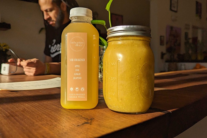 Staff photo by Tierra Hayes / A bottle of cold-pressed juice and a jar of fruit-infused sea moss gel sit on the counter of the Bohemian Village as owner Silas Luster rings up an order.