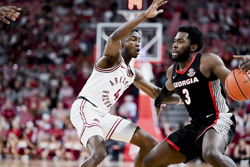 Arkansas guard Davonte "Devo" Davis (4) covers Georgia guard Noah Thomasson (3), Saturday, Feb. 10, 2024, during the first half of a basketball game at Bud Walton Arena in Fayetteville. (Charlie Kaijo/NWA Democrat-Gazette)