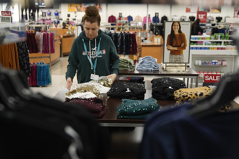 An employee straightens displays at a Kohl's store in Clifton, N.J., Friday, Jan. 26, 2024. A year ago, the store had tables stacked high with sweaters and shirts in a rainbow of colors as well as dress racks crammed with a wide assortment of styles. Now, it boasts a more edited approach — tables have slim piles of knit shirts that focus on fewer colors, and many dress racks have been reduced to just three or four styles. (AP Photo/Seth Wenig)