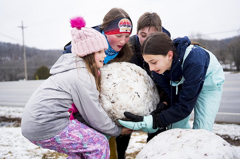 Vivien Fauconniere, 7, (from left), Elaina LaValle, 12, Andre  Fauconniere, 12 and Naomi Fauconniere, 12, build a snow man, Monday, February 12, 2024 at the bottom of a hill at the Bethel Baptist Church in Bentonville. Visit nwaonline.com/photos for today's photo gallery...(NWA Democrat-Gazette/Charlie Kaijo)