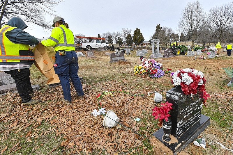 Workers with the City of Fort Smith Parks and Recreation Department remove flowers and other items from around gravestones, Friday, Feb. 9, 2024, at Oak Cemetery in Fort Smith. After months of notifying the public to remove the items ahead of Friday’s deadline, many members of which complied, workers spent the day at the city-run cemetery discarding and bagging leftover items in compliance with the Fort Smith Municipal Code §7-27. Patrick Geels, parks maintenance supervisor, said the ordinance was enforced so that mowers and other maintenance workers can properly maintain the cemetery grounds. Geels added that he understood many people might be upset by the removal of the items, but offered that flower vases and other items that can rest on the gravestones instead of on the grass are still welcome. Any items that were bagged will be placed in storage for reclaiming until March 22, after which they will be discarded. Anyone with questions about the removed items can contact Fort Smith Parks at (479) 784-1006 or fsparks@fortsmithar.gov. Visit rivervalleydemocratgazette.com/photo for today’s photo gallery..(River Valley Democrat-Gazette/Hank Layton)