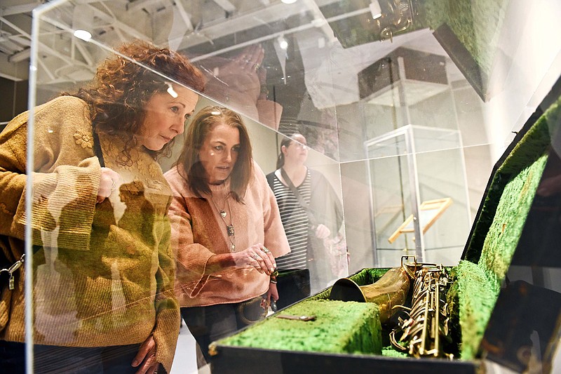 Kelley Cooper of Sherwood (left) and Maria Walker of Little Rock look at Louis Jordan’s saxophone, courtesy of Old State House Museum Collection, during the Arkansongs celebration Sunday at the Windgate Center for Fine and Performing Arts on the University of Central Arkansas campus..(Arkansas Democrat-Gazette/Staci Vandagriff)