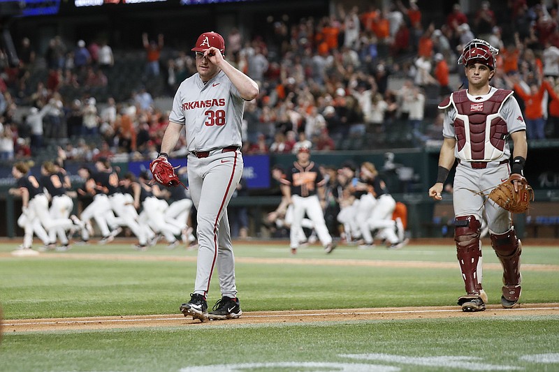 Arkansas pitcher Colin Fisher (38) and catcher Ryder Helfrick walk off the field as Oklahoma State celebrates the game-winning run in the 14th inning Saturday, Feb. 24, 2024, in Arlington, Texas. (James D. Smith/Special to Hawgs Sports Network)