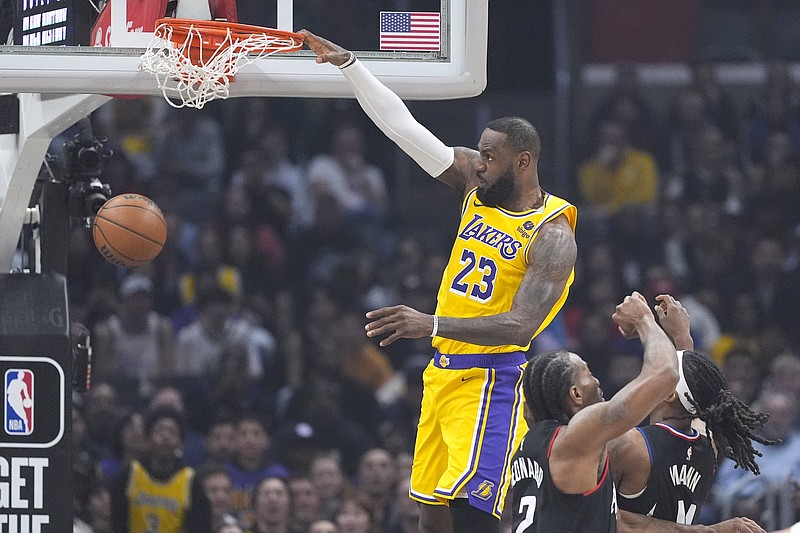 Los Angeles Lakers forward LeBron James, left, dunks as Los Angeles Clippers forward Kawhi Leonard, center, and guard Terance Mann defend during the first half of an NBA basketball game Wednesday, Feb. 28, 2024, in Los Angeles. (AP Photo/Mark J. Terrill)