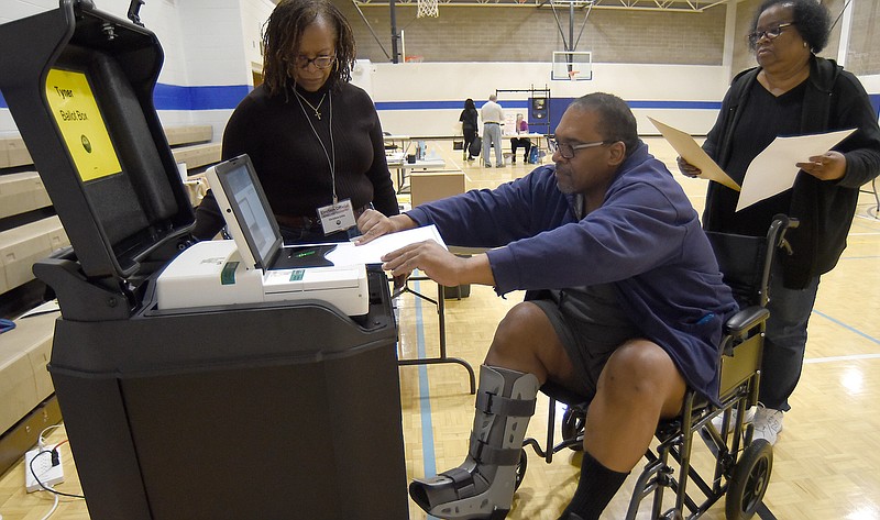Staff photo by Matt Hamilton/ Election official Christine Little, left, looks on as Ronald and Montil Swanson turn in their ballots at the Tyner Community Center on Tuesday.