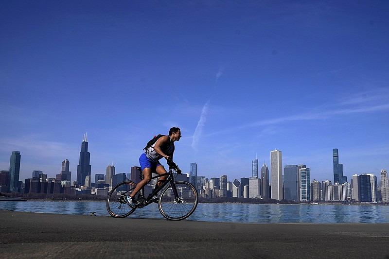 FILE - A cyclist travels around Lake Michigan near the Adler Planetarium Monday, Feb. 26, 2024, in Chicago. Federal meteorologists on Friday, March 8, have made it official: It's the warmest U.S. winter on record by far. (AP Photo/Charles Rex Arbogast, File)