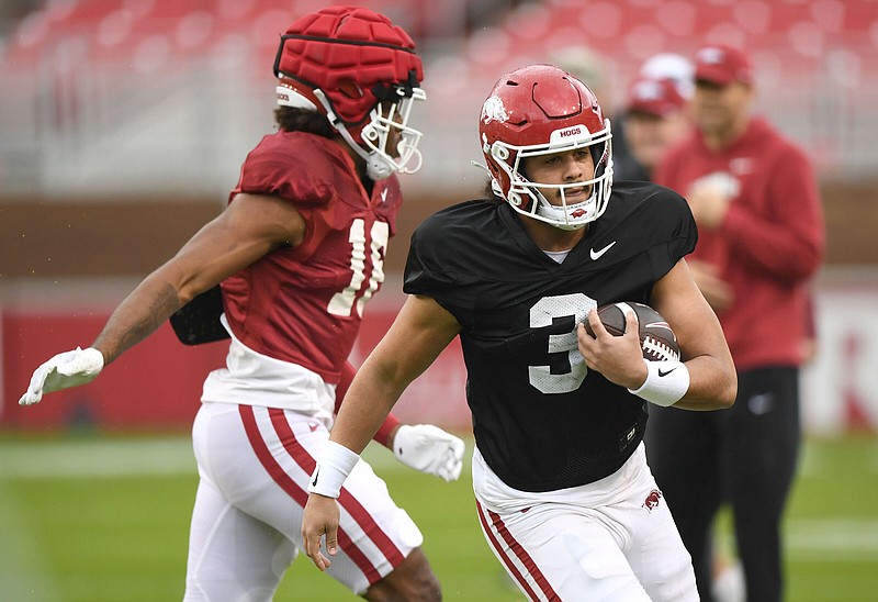 Arkansas quarterback Malachi Singleton (right) runs with the ball Thursday during the Razorbacks’ practice at Reynolds Razorback Stadium in Fayetteville. Singleton threw a 19-yard touchdown pass to wideout Davion Dozier, whose back-handed, one-hand catch at the goal line was the best play of the first five practices of spring. More photos at nwaonline.com/315uaspring/.
(NWA Democrat-Gazette/Andy Shupe)
