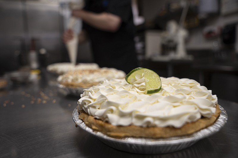 A freshly decorated Key Lime pie rests on a counter in a busy bakery kitchen at Michele's Pies, Wednesday, March 13, 2024, in Norwalk, Conn. Math enthusiasts and bakers celebrate Pi Day on March 14 or 3/14, the first three digits of a mathematical constant with many practical uses. Around the world many people will mark the day with a slice of sweet or savory pie. (AP Photo/John Minchillo)