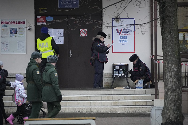 Police officers check the area Friday after a woman threw a Molotov cocktail onto the roof of a school that houses a polling station during a presidential election in St. Petersburg, Russia.
(AP)