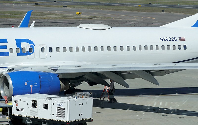 A Medford Jet Center worker walks under a United Boeing 737- 824 that landed Friday at Rogue Valley International-Medford Airport in Medford, Ore., with a missing panel.
(AP/Rogue Valley Times/Andy Atkinson)