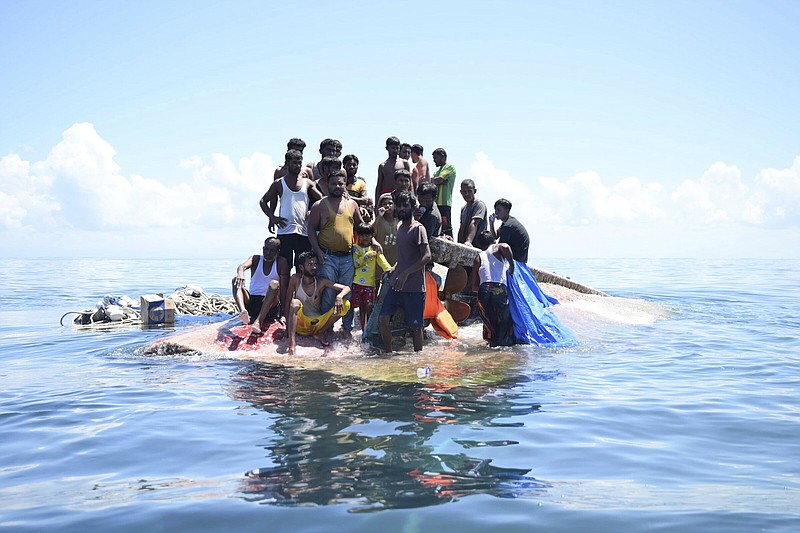 Rohingya refugees stand on their capsized boat before being rescued in the waters off West Aceh, Indonesia, on Thursday.
(AP/Reza Saifullah)