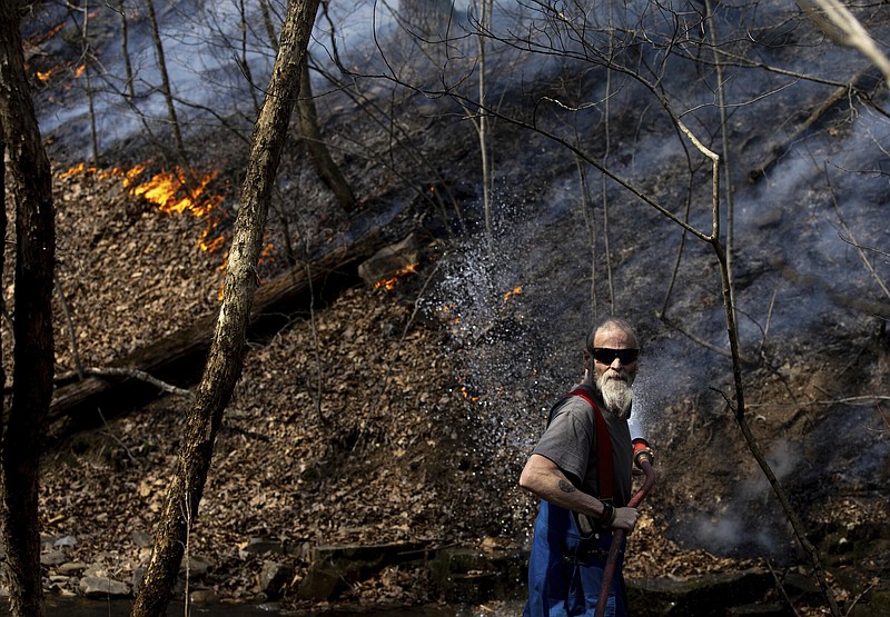 Bergton Volunteer Fire Company firefighter James Morris sprays water on a wildfire Wednesday as it approaches a house on Brushy Run Road in Bergton, Va.
(AP/Daily News-Record/Daniel Lin)