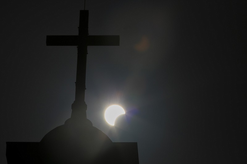 A partial solar eclipse is seen behind a cross on the steeple of a church in this June 21, 2020 file photo. (AP/Hassan Ammar)